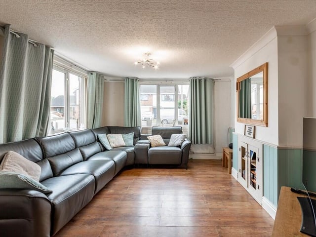 The spacious living room with oak floor and fireplace that could easily be converted back to an open chimney or to house a modern log burner.