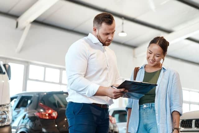 A car buyer discusses finance options with a dealership representative. New research suggests many UK drivers now regret the car finance deals they agreed to in the past decade.