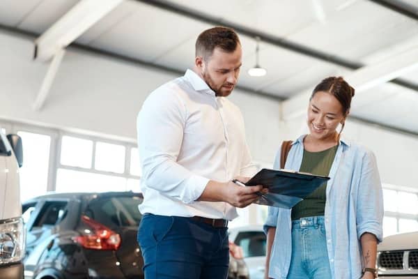 A car buyer discusses finance options with a dealership representative. New research suggests many UK drivers now regret the car finance deals they agreed to in the past decade.
