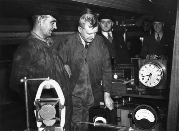 3rd June 1938: Fireman T H Bray on the left and next to him Driver R J Duddington who made history by driving the LNER locomotive 'Mallard' at 125mph. They are in the dynamometer car at Kings Cross station, London studying the instruments which recorded the record-breaking feat. (Photo by Fox Photos/Getty Images)