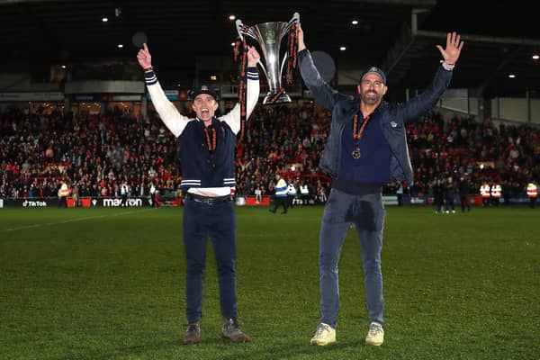 Rob McElhenney and Ryan Reynolds, owners of Wrexham celebrate with the Vanarama National League trophy as Wrexham win the Vanarama National League and are promoted to the English Football League after victory in the Vanarama National League match between Wrexham and Boreham Wood at Racecourse Ground on April 22, 2023 in Wrexham, Wales. (Photo by Jan Kruger/Getty Images)