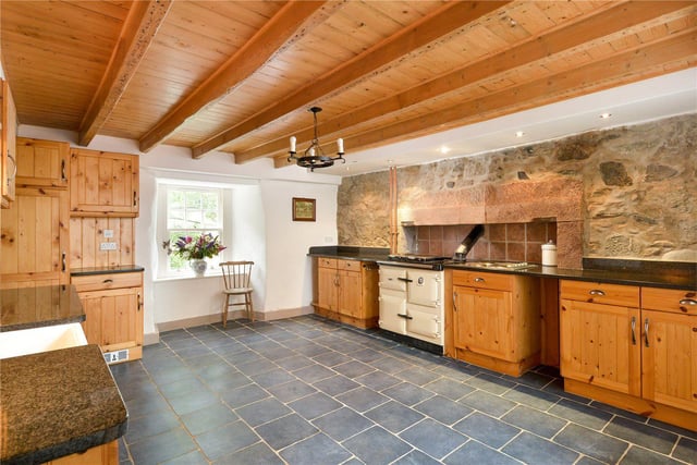 The traditional dining kitchen has a Rayburn stove and exposed stone wall.