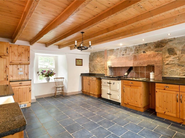 The traditional dining kitchen has a Rayburn stove and exposed stone wall.