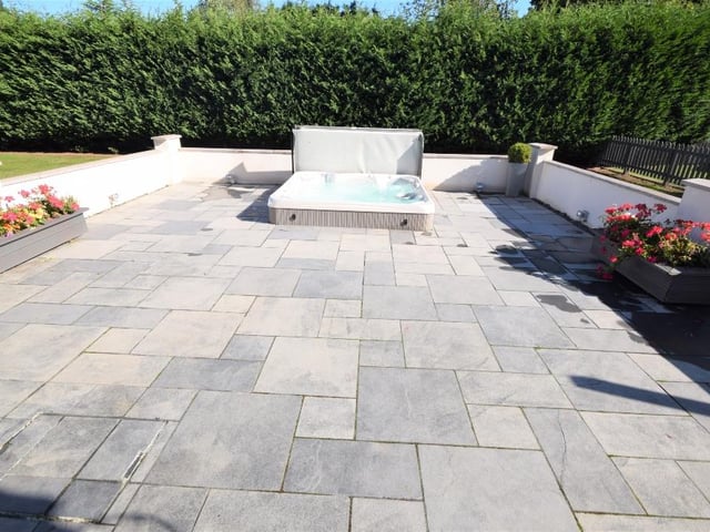 To the rear of the property, there is a paved patio and a sunken hot tub, which is ideal for seating and entertainment.