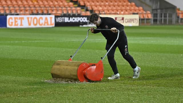 A member of the Blackpool groundstaff attempts to clear water off the pitch at Bloomfield Road ahead of the clash with Rovers