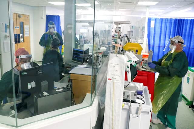 Medical staff wearing full PPE (personal protective equipment), including a face mask, long aprons, and gloves as a precautionary measure against COVID-19, work on an Intensive Care Unit (ICU) ward. (Photo by STEVE PARSONS/POOL/AFP via Getty Images)