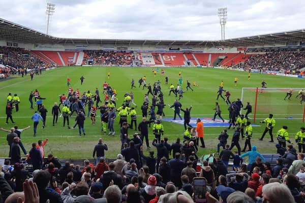 Ecstatic Doncaster Rovers fans invade the pitch during the game with Barrow.