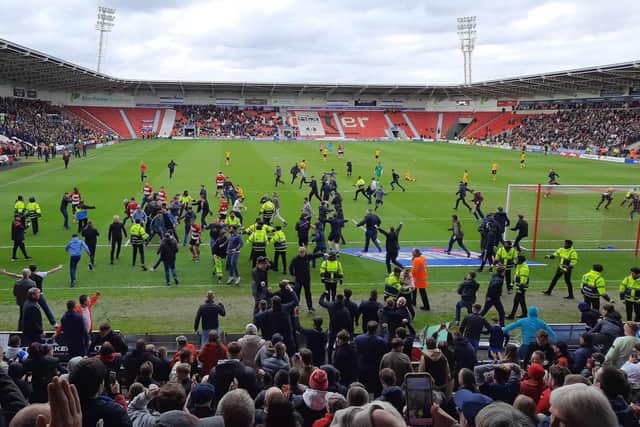 Ecstatic Doncaster Rovers fans invade the pitch during the game with Barrow.