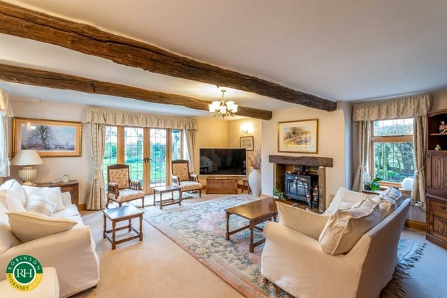 This beamed sitting room has a warming stove, and doors to the garden.