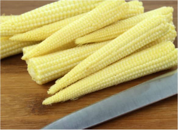 A woman was jailed for stabbing a neighbour who threw sweetcorn at her house.