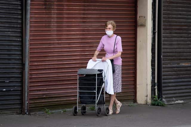 A woman wearing a face face mask walks past closed stores. (Photo by Matthew Horwood/Getty Images)