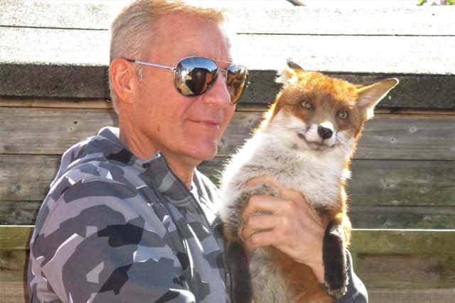Les Hemstock with Ben the fox. See SWNS story SWSYfox. A man adopted an orphaned fox cub after it crawled into his jacket sleeve for a nap. Les Hemstock, 51, was visiting a wildlife sanctuary where a friend was working, when he met a family of cubs brought in by a member of the public. The skulk were starving, freezing and riddled with ticks, and in desperate need of medical attention if they were to survive. One tiny cub - now called Ben - wandered straight over to Les, making a bed in the sleeve of his jacket where he fell fast asleep.