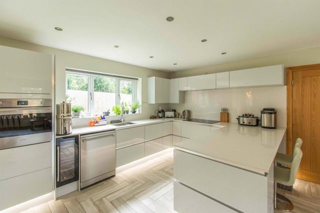 The stylish kitchen has light grey high gloss units with granite worktops.