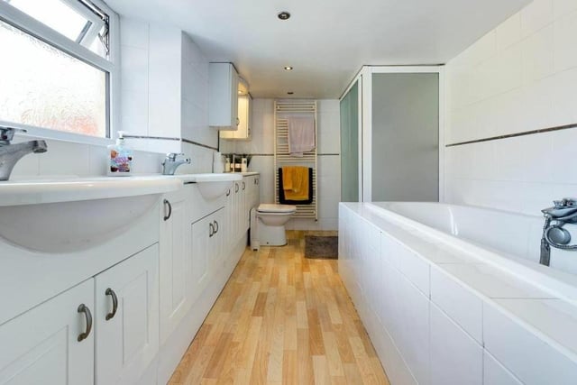 A stylish bath and shower room with twin washbasins.