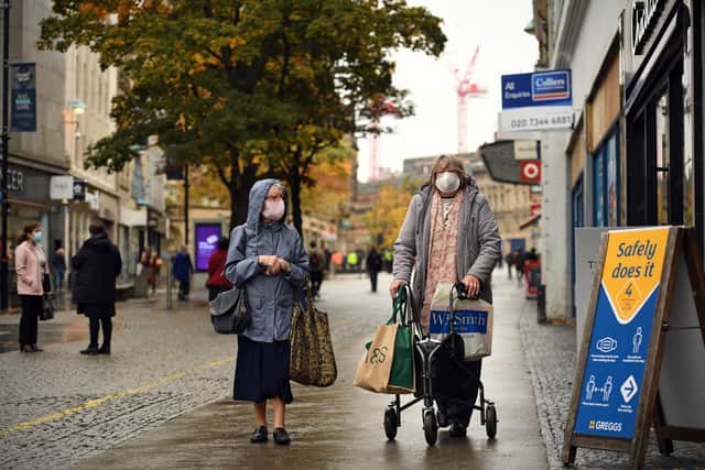 Woman wearing face masks or covering due to the COVID-19 pandemic, walks along the pavement in the shopping district in central Sheffield (Photo by OLI SCARFF/AFP via Getty Images)