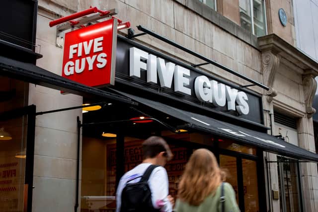 A pedestrian passes a Five Guys hamburger restaurant (Photo credit should read TOLGA AKMEN/AFP via Getty Images)