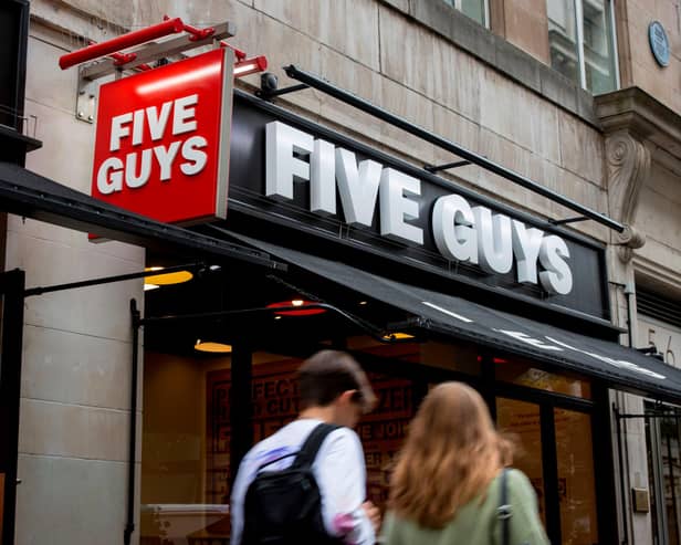 A pedestrian passes a Five Guys hamburger restaurant (Photo credit should read TOLGA AKMEN/AFP via Getty Images)