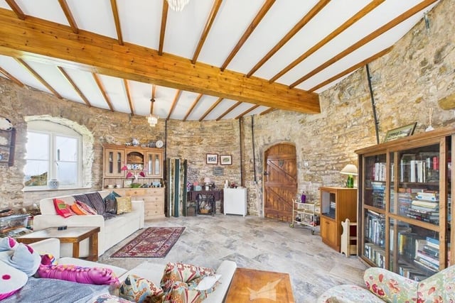 Another view of the beamed living room, with its arched wooden door and deep set windows.