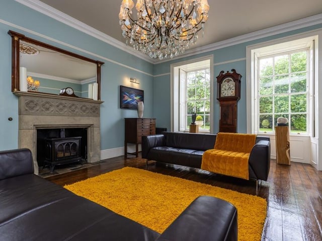 Large windows flood this reception room with feature fireplace with natural light.