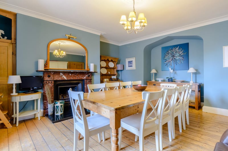 A spacious dining room, also with exposed wooden flooring and a feature open fireplace.