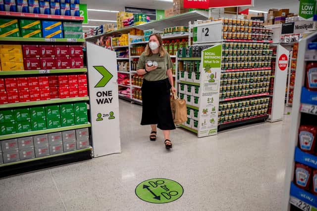 A shopper a face mask as a precautionary measure against spreading COVID-19, walks through a supermarket (Photo by TOLGA AKMEN/AFP via Getty Images)