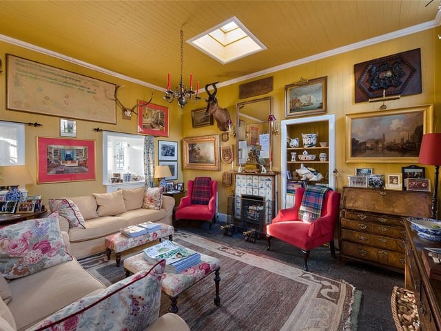 The sunny living room has a tiled fireplace and further views of the castle grounds.