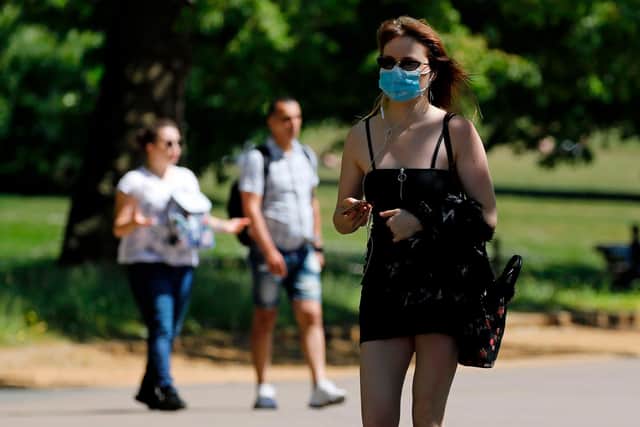 A woman wearing PPE (personal protective equipment), including a face mask as a precautionary measure against COVID-19, walks in the afternoon sunshine (Photo by Tolga AKMEN / AFP) (Photo by TOLGA AKMEN/AFP via Getty Images)