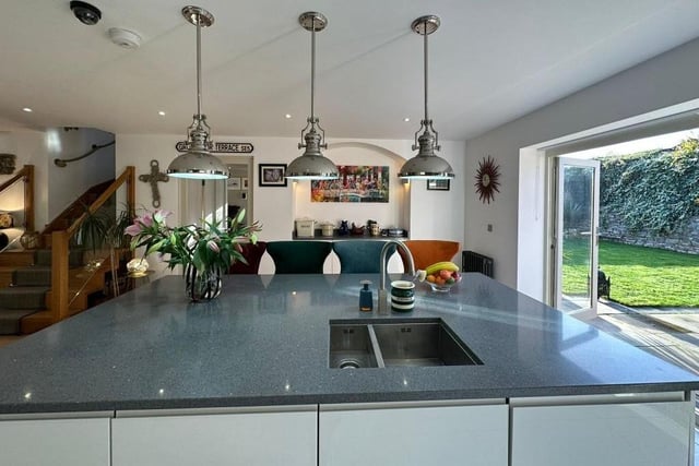 A modern kitchen with a large central island and breakfast bar, and bi-folding doors to an outside patio.