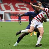 Doncaster's George Miller gets past Wimbledon's Aaron Pierre.