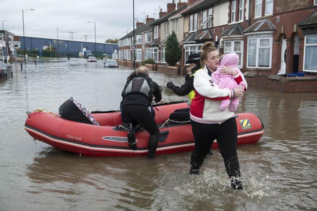 A mother takes her baby to safety after being rescued by boat at Yarborough Terrace in Doncaster as flood waters rise in the area