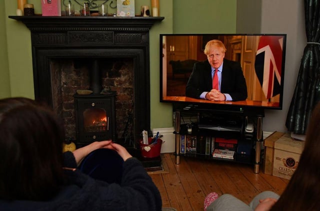 Members of a family listen as Britain's Prime Minister Boris Johnson makes a televised address to the nation from inside 10 Downing Street with the latest instructions to stay at home to help contain the Covid-19 pandemic (Photo: PAUL ELLIS/AFP via Getty Images)