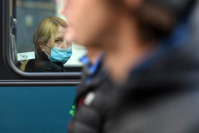 A woman wearing a protective face covering to combat the spread of the coronavirus looks from the window of a bus