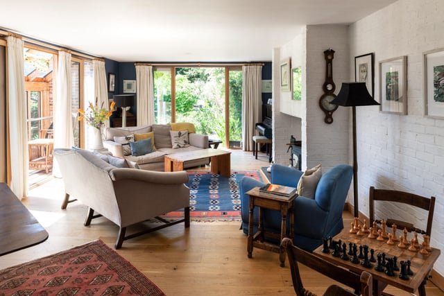 The living room is a "warm and welcoming space", with a log-burning stove at the heart of the room and painted-white brick walls. Glass doors open directly onto the garden at one side, with a second set of glazing doors opening onto the upper conservatory.