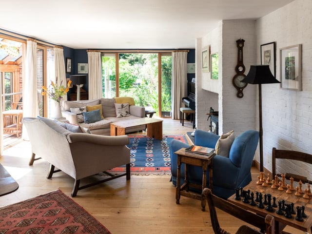 The living room is a "warm and welcoming space", with a log-burning stove at the heart of the room and painted-white brick walls. Glass doors open directly onto the garden at one side, with a second set of glazing doors opening onto the upper conservatory.