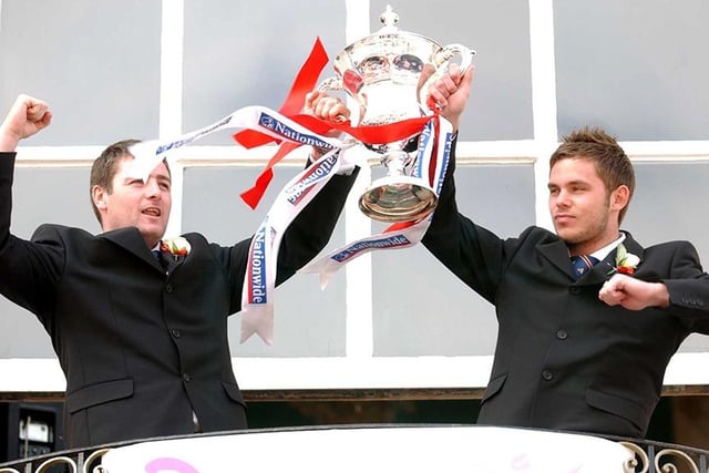 Players show off the trophy from the Mansion House balcony