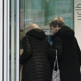 Two women walk past a sign providing guidance information about novel coronavirus (COVID-19) at one of the entrances to University College Hospital in London. (Photo by ISABEL INFANTES/AFP via Getty Images)