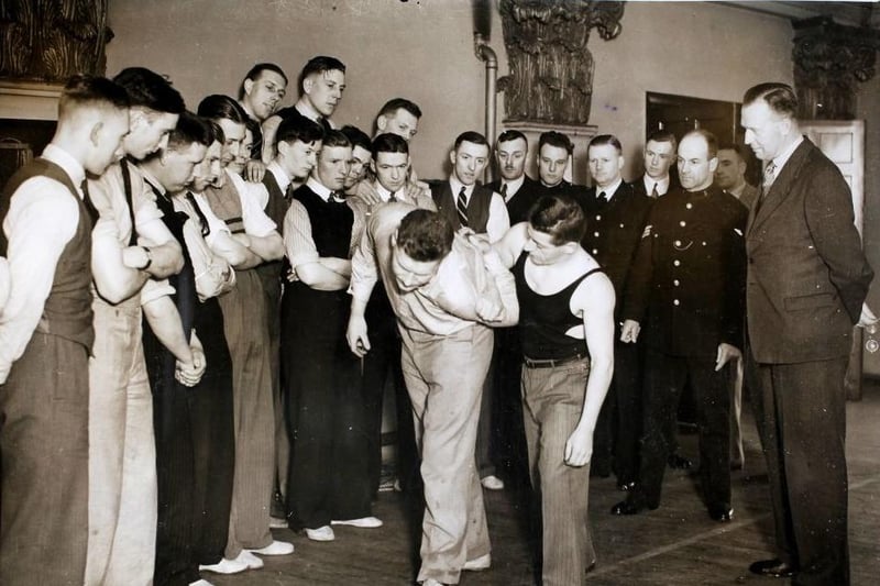 Harold Angus, the British and European Welterweight Wrestling Champion, demonstrates a hold for arresting a violent suspect to new recruits of the Doncaster County Borough Police Force at the Guild Hall, Doncaster on 23th May 1936. On the right is the Chief Constable, Mr J Clayton.