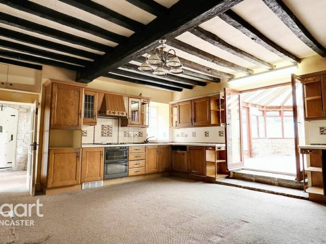 A spacious beamed kitchen with fitted units has doors to the dining room and the conservatory.