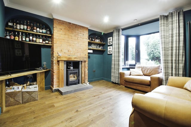 The stylish lounge has a fireplace feature with a log burner, and a bay window.