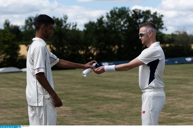 Shahryar Kahn of Hambledon CC (left) squirts out some hand sanitiser during an interval. Picture: Jordan Pettitt/Solent News & Photo Agency