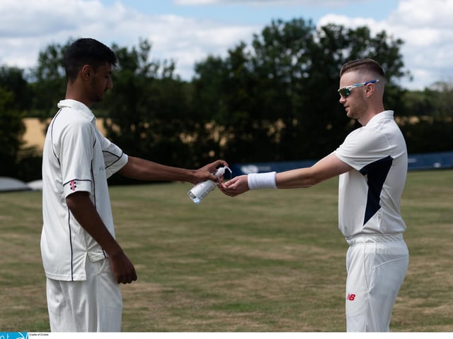 Shahryar Kahn of Hambledon CC (left) squirts out some hand sanitiser during an interval. Picture: Jordan Pettitt/Solent News & Photo Agency