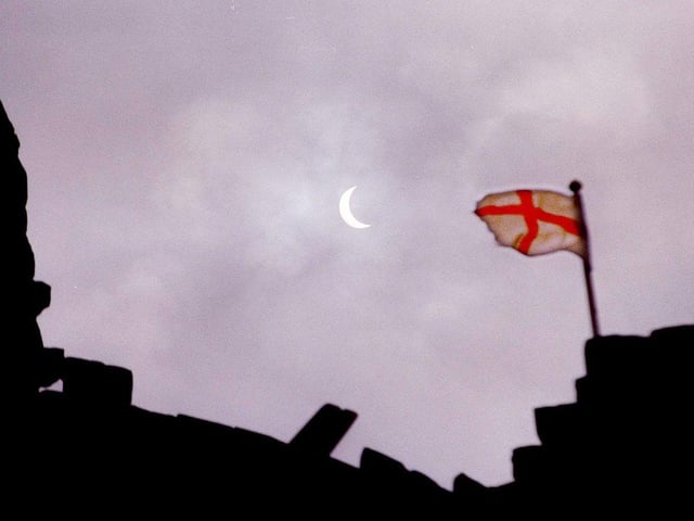 The solar eclipse seen from the grounds of Conisbrough Castle. The flag is that of St George which flies from the top of the keep, August 11, 1999
