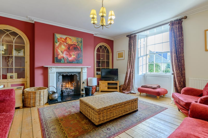 A spacious sitting room with exposed wooden flooring and a feature open fireplace.