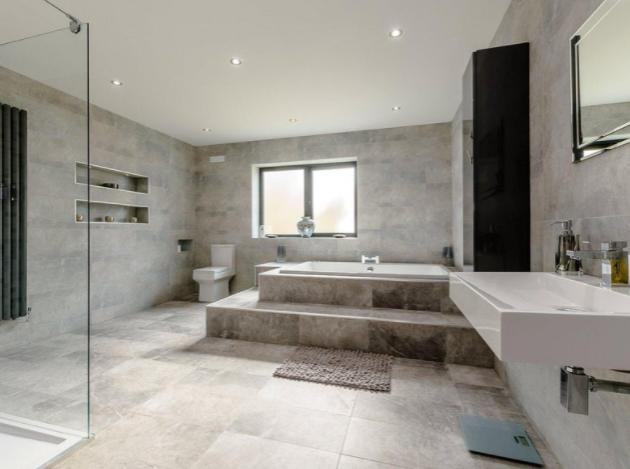 The large family bathroom benefits from a walk-in shower, huge bath, toilet and sink, and modern marble-effect tiling.
