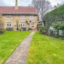 The property as viewed from the garden, with its wide terrace or patio area directly by the house.