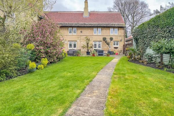 The property as viewed from the garden, with its wide terrace or patio area directly by the house.
