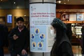 A woman wearing a face mask passes a Public Health England sign, warning arriving passengers that a virus, Coronavirus, has been detected in Wuhan in China, at Terminal 4 of London Heathrow Airport in west London on January 28, 2020. - Chinese President Xi Jinping said Tuesday the country was waging a serious fight against the "demon" coronavirus outbreak and pledged transparency in the government's efforts to contain the disease. (Photo by DANIEL LEAL-OLIVAS/AFP via Getty Images)