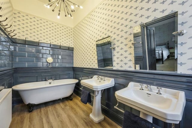 This bathroom suite includes double washbasins and a freestanding roll-top bath.