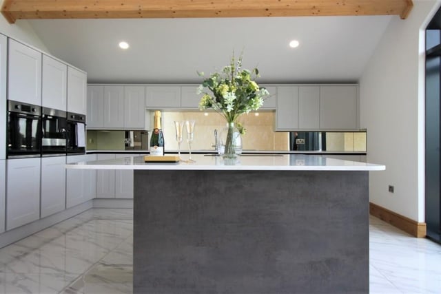Pale grey units and white granite worktops, with integrated appliances, are fitted in the high spec kitchen that has a glass wall to maximise the views.