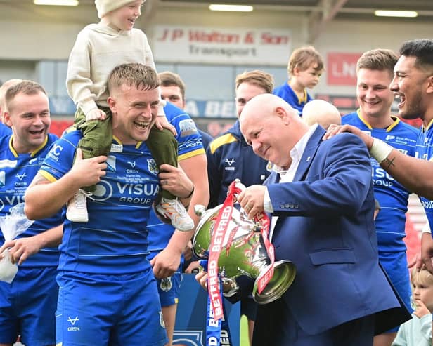 Dons chief executive Carl Hall celebrates promotion with the players.